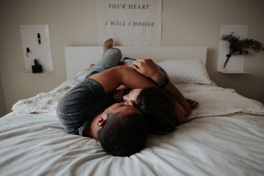 Un homme et une femme se blottissant l'un contre l'autre dans un lit.